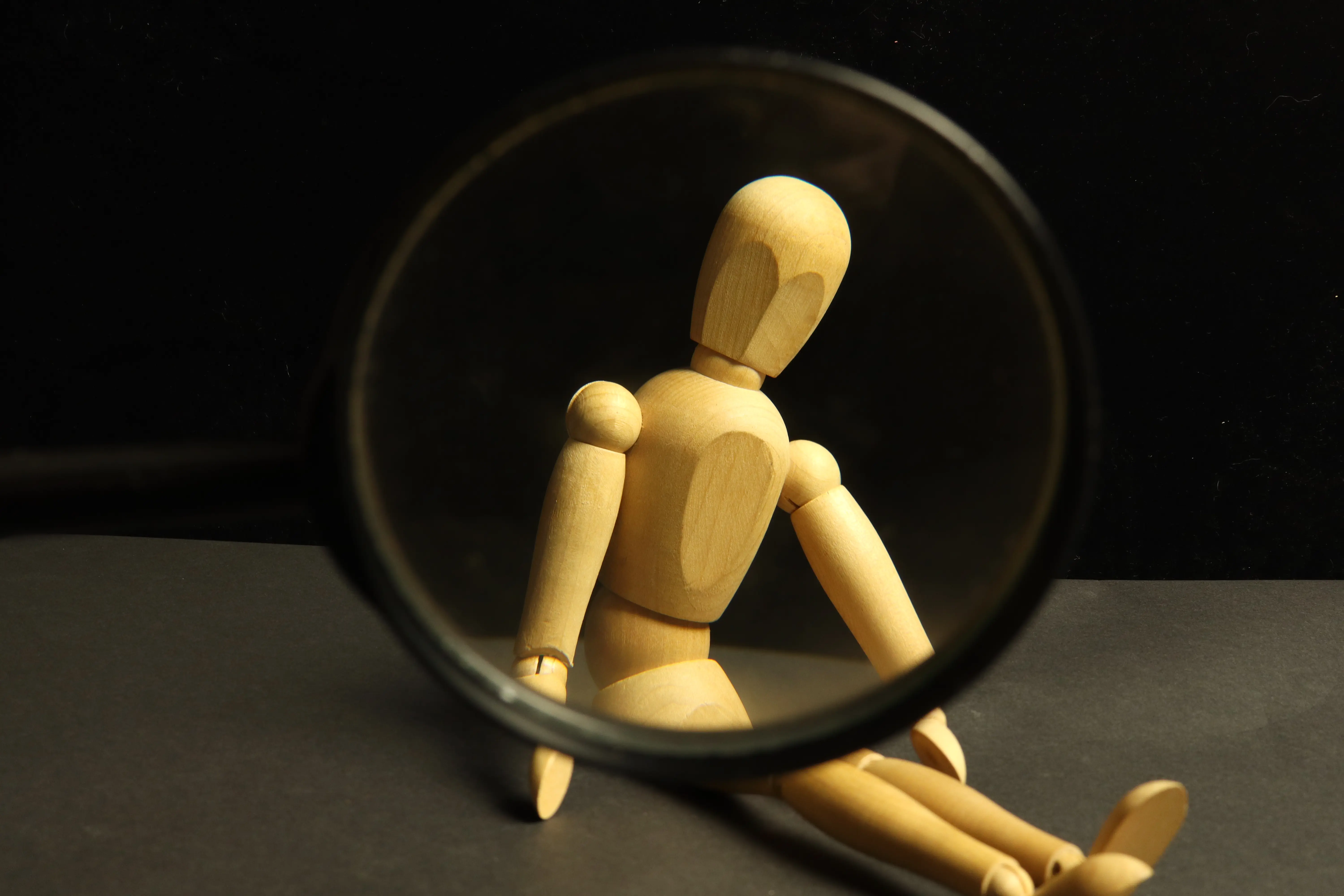Wooden doll inside a magnifying glass